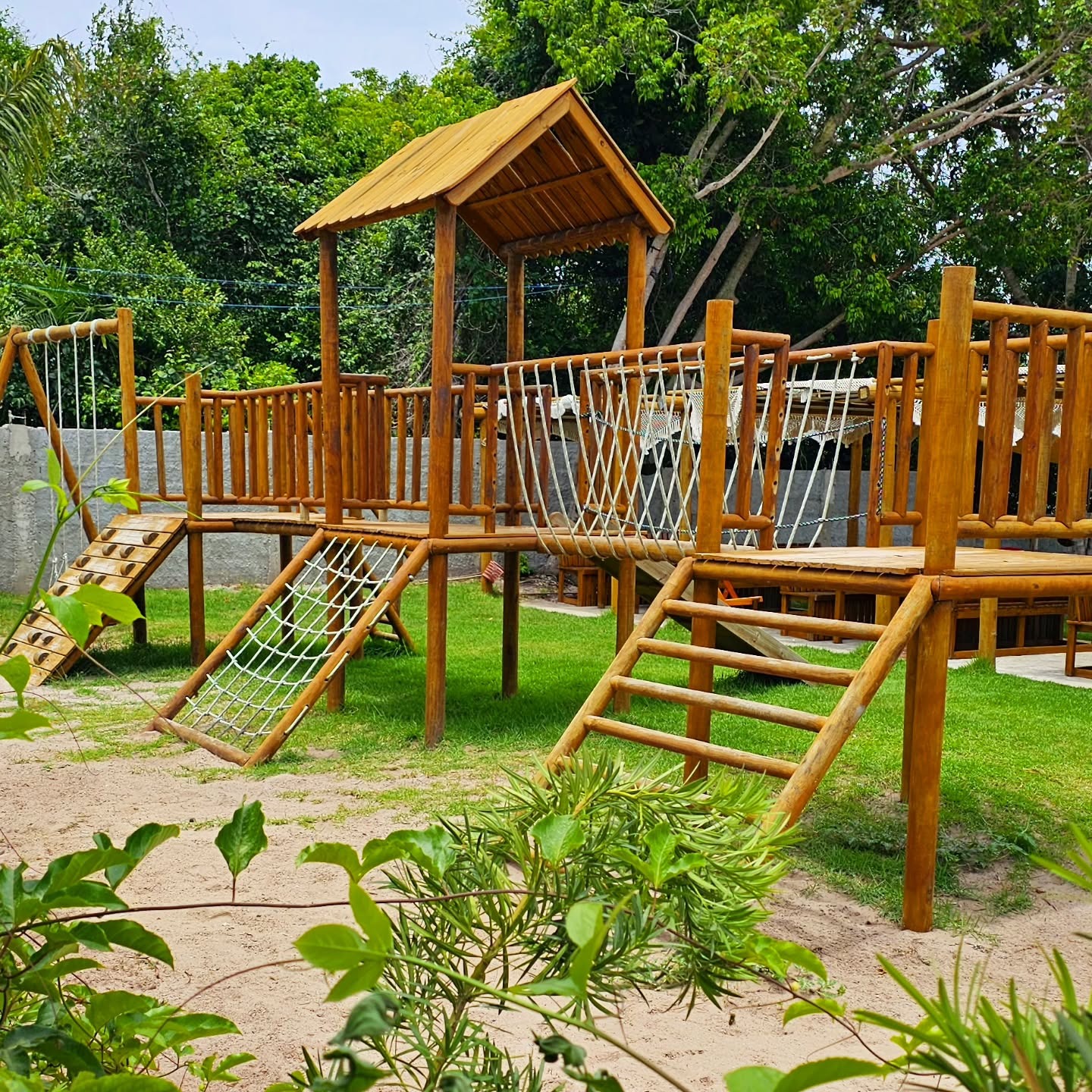 Playground de madeira com ponte de corda e escorregador na área kids do Paraíso dos Tambaquis em Estância/SE